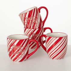 four red and white striped coffee mugs stacked on top of each other with the words merry christmas written on them