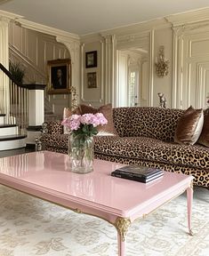 a living room with leopard print couches and pink coffee table in front of a staircase