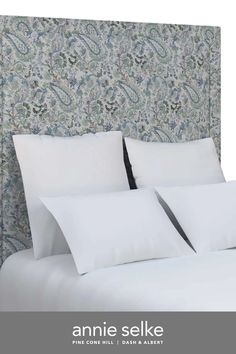 an image of a bed with white sheets and pillows on top of the headboard