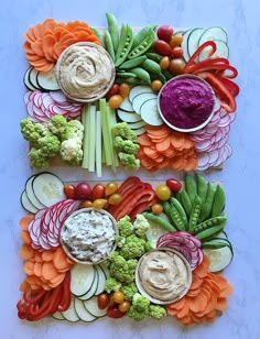 two trays filled with veggies and dips on top of each other