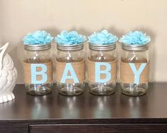 four mason jars with blue flowers are sitting on a table next to a white owl