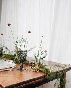 the table is covered with flowers and greenery on it, along with other items