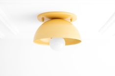 a yellow light fixture hanging from the ceiling in a room with white walls and ceilings