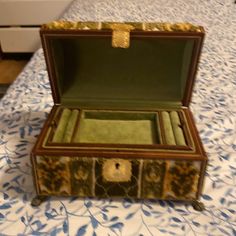 an open wooden box on a blue and white patterned tablecloth with gold trimmings