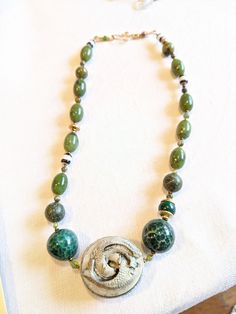 Amazing two fish center piece inspired this Agate , jade and gold necklace. Older striped Czech beads, peridot and malachite beads meant for "HARMONY and ABUNDANCE" Green Jade Amulet Necklace, Spiritual Jade Jewelry With Large Beads, Green Agate Jewelry With Natural Stones, Large Jade Bead Jewelry, Unique Jade Beaded Necklace With Round Beads, Nature-inspired Green Jade Necklaces, Green Agate Pendant Necklace, Green Jade Natural Stones Beads, Green Amulet-style Round Bead Jewelry