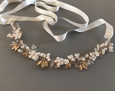 "Elegant Freshwater Pearl floral bridal sash for your most romantic day! This hand wired wedding belt combines soft white enamel flowers, tiny shell flowers Freshwater Pearls, crystal beads and small gold stamped leaves. It brings elegant style to botanical beauty and would be beautiful with many wedding themes. READY TO SHIP DETAILS * Measures aprox.1.5\" wide (at widest part) by 13\" long. * Attached at ends to imported French satin ribbon in choice of colors. * Total sash length 3 yards. * Of Elegant Bridal Belt With Flower Decoration For Wedding, Elegant Embroidered Bridal Belt For Evening, White Adjustable Wedding Sashes, Adjustable Handmade Flowers Bridal Accessories, Elegant Bridal Belt With Flower Decoration, Elegant Bridal Belt With Handmade Flowers For Weddings, Elegant Embellished Adjustable Bridal Belt, Silver Bridal Belt With Pearl Embroidery For Wedding, Elegant Bridal Belt With Handmade Flowers