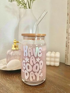 a glass jar with a straw in it sitting on a table next to a vase