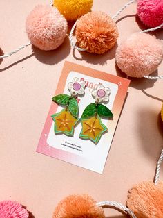 some pom poms are laying on top of a pink and yellow table cloth