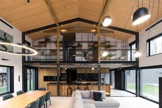 a living room filled with furniture and lots of windows next to a wooden ceiling covered in hanging lights