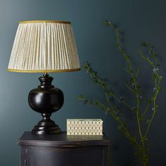 a lamp sitting on top of a wooden table next to a vase with purple flowers