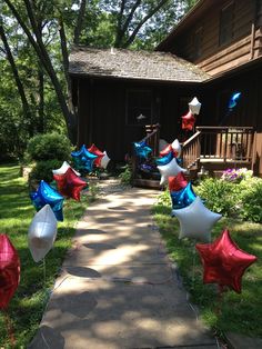 some red, white and blue balloons are in the grass near a house on a sunny day