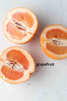 three oranges cut in half on a white counter top with the words grapefruit written below them