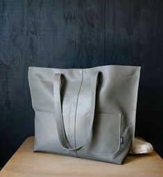 "Large gray handmade leather market tote purse is ready to ship. Large simple modern tote purse with exterior pocket and contrasting pink stitching. Leather tote is perfect for a market, library, portfolio or travel bag. -Dimensions: 19.5\" wide x 14\" high x 4.5\" deep -Strap length: 13\" - Pocket size: 5\" wide x 6\" high -GREEN DESIGN- This Tote is made from \"up-cycled\" leather, not recycled. We sought out upholstery, interior design & fabric shops' leftovers to construct this bag. This is newly treated & constructed leather, not used, that potentially otherwise would end up in a land fill. So when you purchase one, wear it proudly!" Gray Leather Shopping Bag, Gray Bags With Leather Handles, Leather Bag With Silt Pocket For Everyday Use, Gray Leather Shoulder Bag With Large Capacity, Gray Leather Rectangular Shoulder Bag, Gray Leather Shoulder Bag For Daily Use, Soft Leather Gray Bag, Gray Leather Bag For Everyday Use, Gray Leather Shoulder Bag With Double Handle