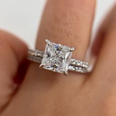 a woman's hand with a diamond ring on top of her finger and an engagement band