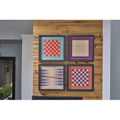 four squares are hanging on the wall in front of a door with wood paneling