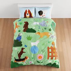 a bed covered in a green comforter with dogs on it