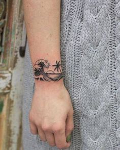 a woman's wrist with a tattoo on it that has a wave and palm trees