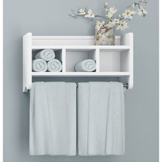 a white shelf with towels and flowers on it