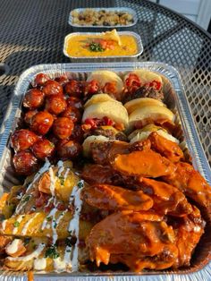 there are many different types of food in the trays on the table, including chicken wings and bread