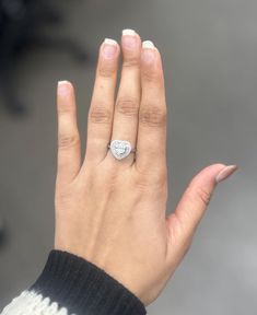 a woman's hand with a diamond ring on her left hand and white nails