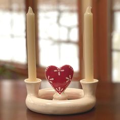 two candles are sitting on a plate with a heart shaped candle holder