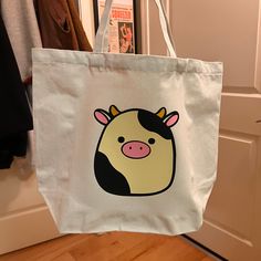 a white bag with a cartoon cow on it hanging from a hook in front of a door