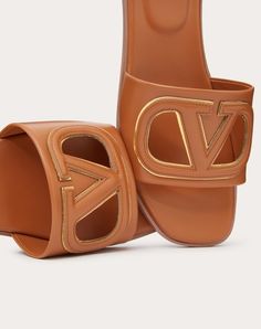 Valentino Garavani VLogo cut-out slide sandal in calfskin leather - VLogo Signature cut-out calfskin detail with mirror-effect trim - Insole with padded heel for extra comfort - Heel height: 5 mm / 0.2 in. - Made in Italy Luxury Slide Mules, Luxury Calf Leather Slides With Leather Footbed, Luxury Slides With Leather Footbed And Calf Leather, Luxury Slides With Calf Leather Footbed, Designer Calf Leather Slides With Leather Lining, Designer Leather Slides With Leather Lining, Luxury Brown Slides With Leather Sole, Luxury Slide Mules With Leather Footbed, Luxury Slides With Leather Footbed