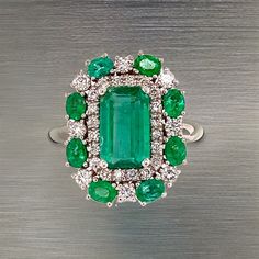 This One-of-a-Kind, Custom-Made Natural Emerald and Diamond Ring is a luxurious piece designed to captivate. Crafted in 14k gold, it showcases a finely faceted, high-quality natural emerald as the center stone, radiating deep green elegance and sophistication. The emerald is complemented by a stunning arrangement of brilliant diamonds that enhance its color and sparkle. Sized at 6.5 and resizable for a perfect fit, the ring has an impressive total carat weight (TCW) of 4.52 carats. Certified and Green Platinum Gemstones Fine Jewelry, Fine Green Platinum Gemstones Jewelry, Green Diamond Platinum Ring Fine Jewelry, Oval Multi-stone Emerald Ring In Platinum, Classic Multi-stone Green Gemstones, Green Cluster Diamond Ring Fine Jewelry, Green Platinum Diamond Ring, Fine Jewelry Green Diamond Ring In Platinum, Fine Jewelry Green Diamond Platinum Ring