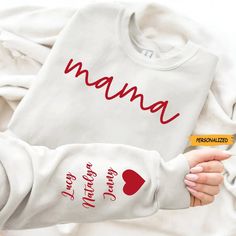 a woman holding a baby in her arms with the words mama printed on it's sleeves