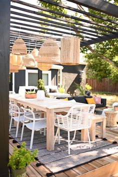 an outdoor dining table and chairs on a deck with lights hanging from the ceiling over it