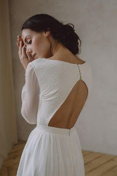 a woman in a white dress is looking out the window and holding her hand to her face