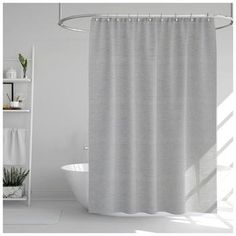 a bathroom with a white tub and shower curtain next to a shelf filled with plants