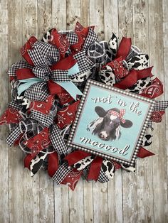 a red and black wreath with a cow on it that says, sweet in the wool