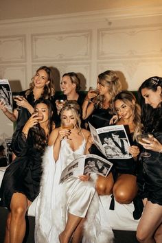 a group of women in dresses posing for a photo with their cell phones and magazines