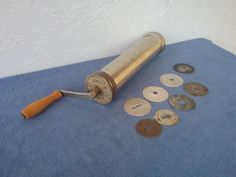 an assortment of old metal buttons on a blue cloth with a rolling pin and wooden handle