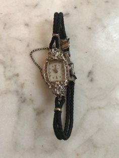 "A lovely antique ladies Hamilton wrist watch which is a fresh estate find. Very nice original condition & seems to be in working order when wound. Impressed on reverse 14k white gold with diamond accents on each side of the watch face. Very dainty, petite & elegant. Measures: 6.5\" length" Handmade Luxury Vintage Watch Accessories, Antique Hallmarked Diamond Watch, Antique White Gold Collectible Watch, Antique Diamond Watch With Diamond Hour Markers, Collectible White Gold Elegant Watches, Elegant Collectible White Gold Watches, Elegant White Gold Collectible Watches, Antique Engraved White Gold Diamond Watch, Antique Diamond Watch For Evening