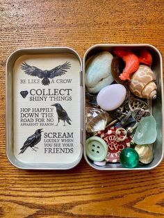 an open tin with buttons and other items in it on a wooden table next to a pair of scissors