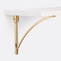 a white shelf with gold brackets on it