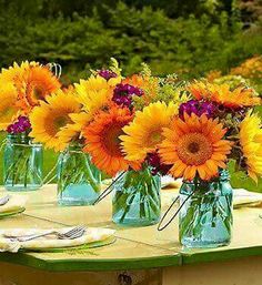 sunflowers are in mason jars on an outdoor table