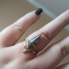 a woman's hand with a ring on it and an arrow shaped diamond in the middle