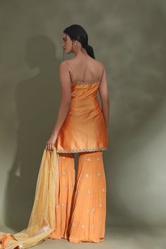 Dance the night away at weddings in this beautiful orange embroidered sharara suit. It comes with a matching dupatta. Shop designer suits in USA from Pure Elegance. DISCLAIMER: The actual product may vary slightly from the image. These are custom orders, hence expect slight variation in color and placement of the motif or buta. ESTIMATED DELIVERY: Because this is a custom order, it would take about 4 weeks from the date of purchase. RETURN POLICY: This product is a custom order and cannot be ret Orange Designer Palazzo Set For Navratri, Traditional Drape Orange Palazzo Set With Dupatta, Orange Palazzo Set With Dupatta And Traditional Drape, Semi-stitched Orange Palazzo Set With Gota Work, Designer Orange Palazzo Set With Zari Work, Orange Palazzo Saree Set For Diwali, Traditional Orange Palazzo Set With Gota Work, Semi-stitched Orange Palazzo Set With Zari Work, Orange Bollywood Designer Palazzo Set