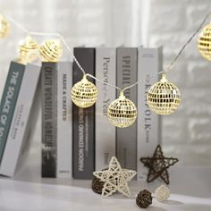 christmas lights hanging from a string on a bookshelf next to other decorations and books