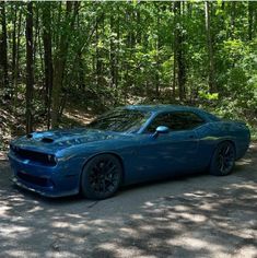 a blue sports car parked on the side of a road in front of some trees