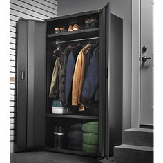 an open storage cabinet with clothes hanging on it