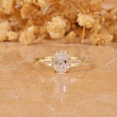 a diamond ring sitting on top of a table next to dried flowers and twigs in the background