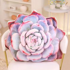 a pink and blue flower sitting on top of a white chair