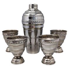 a set of four silver goblets sitting next to each other on a white background