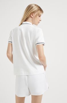 The comfortable-looking cotton interlock fabric is characterized by a soft and compact hand. Ribbed collar with button opening White Polo Shirt With Ribbed Collar For Work, Elegant White Polo Shirt With Ribbed Collar, Classic White Polo Shirt With Contrast Collar, Elegant White Polo Shirt For Work, Sporty Cotton Polo Shirt With Collared Neckline, White Sporty Polo Shirt With Collared Neckline, White Sporty Polo Shirt With Contrast Collar, White Cotton Polo Shirt With Ribbed Collar, White Top With Contrast Collar