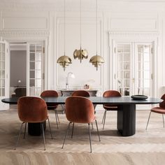 an elegant dining table and chairs in a room with white walls, wood flooring and gold pendant lights