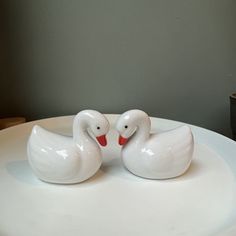 two ceramic ducks sitting on top of a white plate